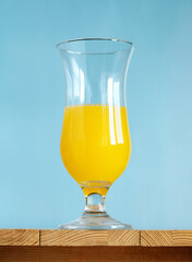 glass with a yellow drink on a blue.