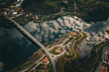 Aerial view of a ring road a river with cloud reflection and a bridge