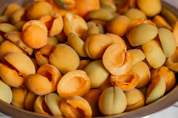 Fototapeta na wymiar Close up of ripe orange and yellow apricots.Pile of fresh,juicy apricots scattered in bowl.Background,texture of fruit halves,slices the workpiece to jam.Summer harvest,canning concept.Farmer worked
