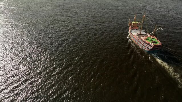 Side view of old sailing ship motoring through open water on sunny day