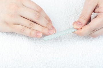 Close-up corrects the shape of the nails with a nail file.