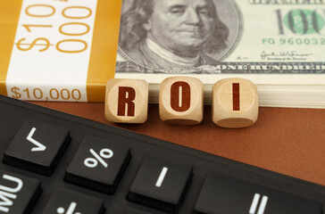 On the table are dollars, a calculator and cubes with the inscription - ROI