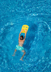 Boy child swim in swimming pool using board. Active wellness summer vacation in resort hotel. Water...