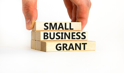 Small business grant symbol. Concept words Small business grant on wooden blocks on a beautiful white table white background. Businessman hand. Business, finacial and small business grant concept.