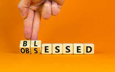 Blessed or obsessed symbol. Businessman turns wooden cubes and changes the concept word Obsessed to Blessed. Beautiful orange table orange background. Business blessed or obsessed concept. Copy space.