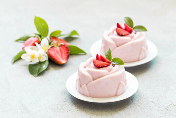 Fototapeta na wymiar Strawberry cream pudding, Panna Cotta, in the shape of a rose, on a plate. Light grey background