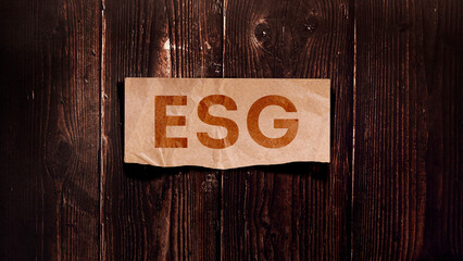 "ESG" Environmental Social Governance. Message for card, presentation and work. Rustic design on wooden background with kraft paper cut out. Can be used for business, marketing and advertising.