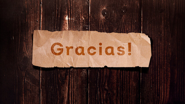"Gracias" escrito em papel kraft design para apresentação com fundo de madeira.