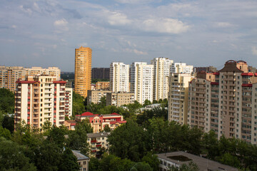 Fototapeta na wymiar Beautiful urban landscape with modern high-rise buildings, green lush foliage of trees and a church in Reutov Moscow region Russia on a summer day