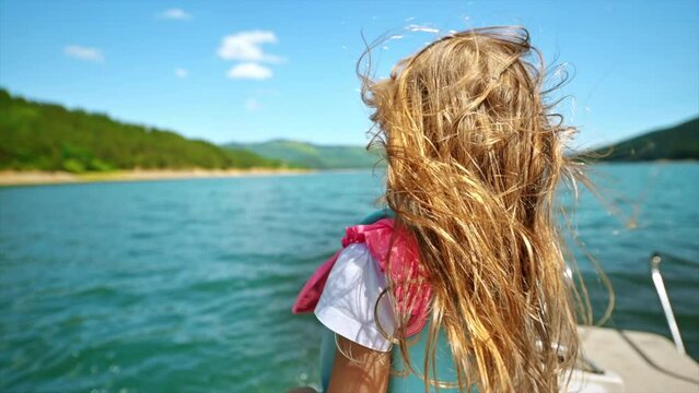 A girl at floating boat on Lake Izvorul Muntelui located in a valley in the Carpathians, Romania. Slow motion blowing hair