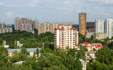 City landscape - modern tall houses among green trees in Reutov in the Moscow region on a summer day and cloudy sky