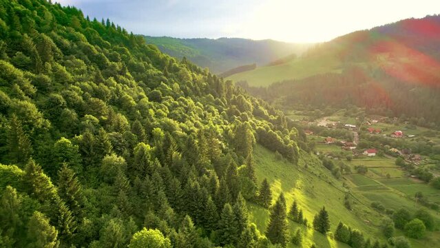 Aerial drone view of nature in the Carpathians in Romania. Village located in a valley, hills covered with lush forest