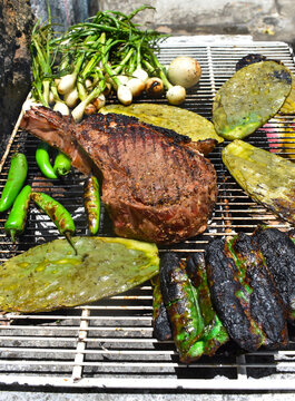 Vertical image of a grilled meat with onions, nopales and green chorizo