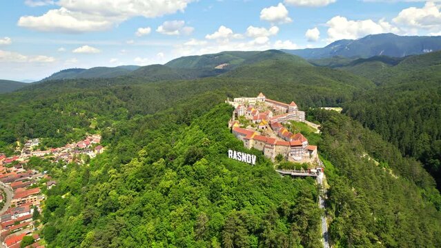 Aerial drone view of The Rasnov Fortress in Romania. Medieval fortress with Rasnov inscription on the top of the hill and town, Carpathians