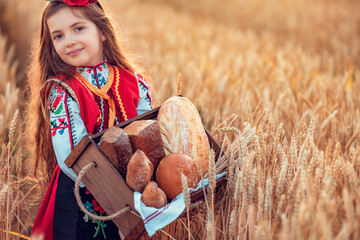 Beautiful girl woman in traditional Bulgarian folklore dress holding wicker basket with homemade...
