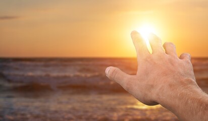 Human hand to sun on sky background
