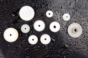 white plastic gears on a dark background. connection mechanism details. subject of movement