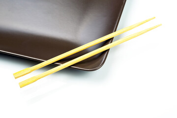 bamboo chopsticks lie on a ceramic plate. items for food