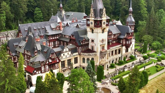 Aerial drone view of The Peles Castle in Romania. Castle with gardens and tourists in Carpathians, lush forest around it