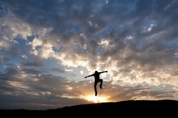 Happy human jumping on the top of mountain, celebrating success outdoor