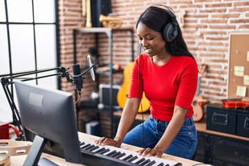 Young african american woman musician playing piano keyboard at music studio