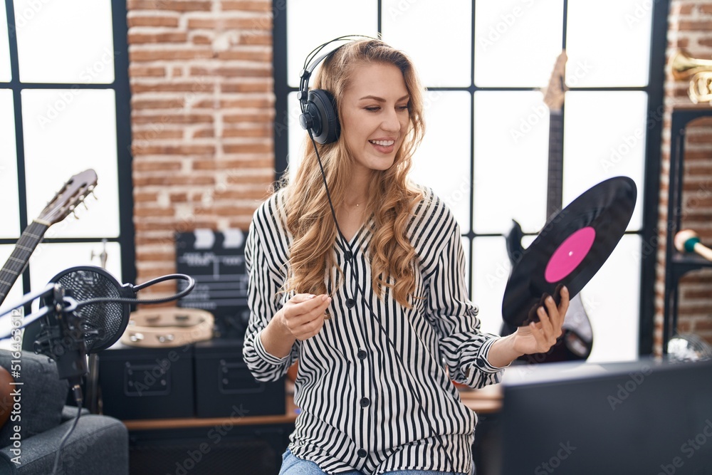 Poster Young blonde woman dj holding vinyl disc at music studio