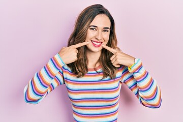 Young hispanic girl wearing casual clothes smiling cheerful showing and pointing with fingers teeth and mouth. dental health concept.