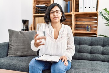 Obraz premium Young latin woman having psychology session offering water at psychology center