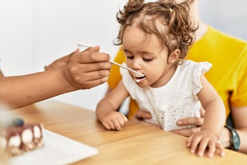 Naklejka premium Couple and daughter having breakfast sitting on table at home