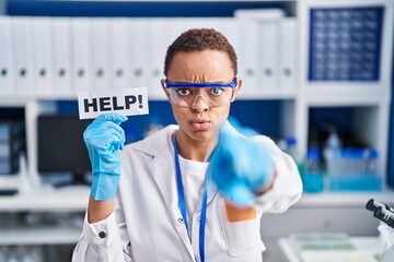 Fototapeta premium Beautiful african american woman working at scientist laboratory asking for help pointing with finger to the camera and to you, confident gesture looking serious