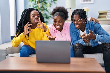 African american friends having video call sitting on sofa at home