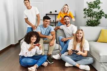 Group of young friends smiling happy playing video game at home.