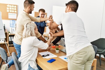 Obraz premium Group of business workers smiling happy celebrating making tower with fists together at the office.