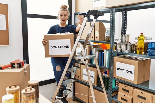 Young caucasian woman volunteer holding donations box doing stop gesture with hands palms, angry and frustration expression