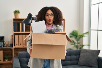 Young african american woman moving to a new office holding box with items afraid and shocked with surprise and amazed expression, fear and excited face.