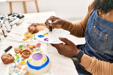 African american artist man mixing color on palette at art studio.