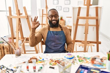 African american artist man at art studio smiling positive doing ok sign with hand and fingers. successful expression.