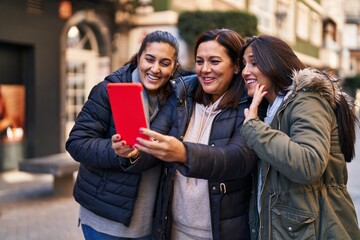 Obraz premium Three woman mother and daughters having video call at street