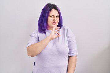 Plus size woman wit purple hair standing over isolated background disgusted expression, displeased...