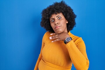 Obraz na płótnie Canvas Black woman with curly hair standing over blue background cutting throat with hand as knife, threaten aggression with furious violence