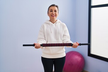 Middle age woman smiling confident training using bar at sport center