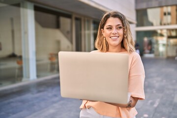 Young hispanic woman smiling confident using laptop at street
