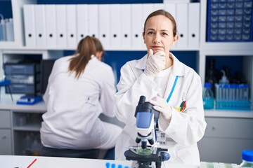 Blonde woman working on cruelty free laboratory serious face thinking about question with hand on...