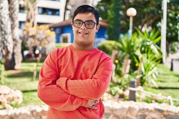 Down syndrome man smiling confident standing with arms crossed gesture at park
