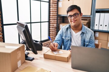 Down syndrome man ecommerce business worker writing on package at office
