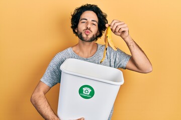 Handsome hispanic man recycling banana peel composting organic fertilizer looking at the camera...