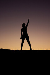 silueta de una mujer levantando el puño como victoria