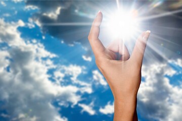 Human hand to sun on sky background