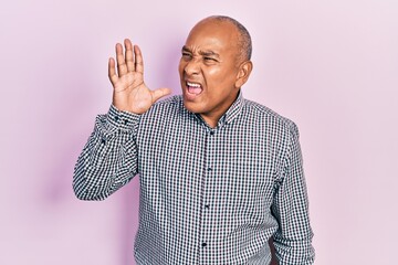 Middle age latin man wearing casual clothes shouting and screaming loud to side with hand on mouth. communication concept.