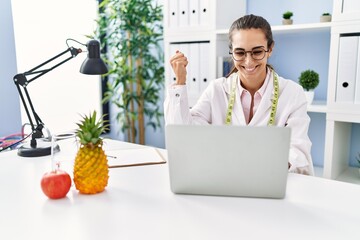 Young hispanic woman working at dietitian clinic screaming proud, celebrating victory and success...